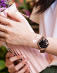 roségoldene Uhr mit schwarzem Ziffernblatt und Blumenmuster