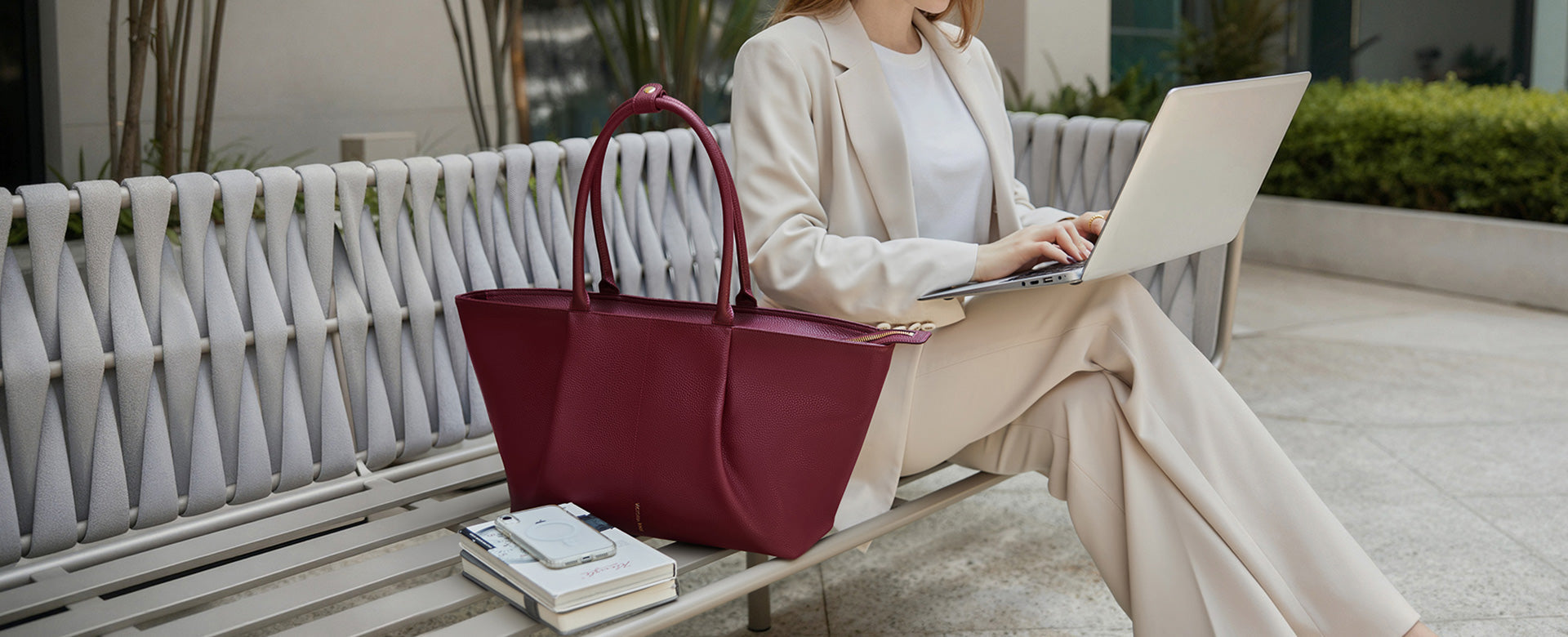 Eine Frau arbeitet mit einem Laptop neben der roten Ada Tasche von Victoria Hyde London – eine elegante Tote Bag für Arbeit, Business und den modernen Alltag.