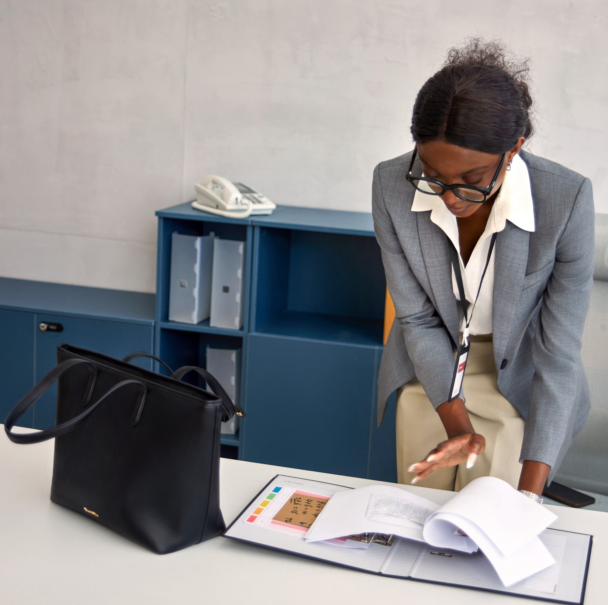 Frau arbeitet im Büro mit schwarzer Victoria Hyde Business-Tasche auf dem Schreibtisch – moderne, nachhaltige Damenhandtasche für Beruf und Organisation.
