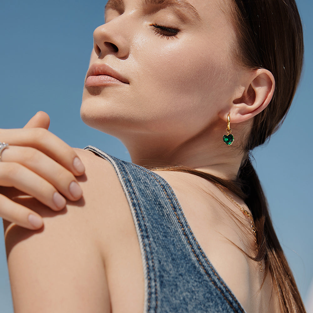 Victoria Hyde London heart-shaped jewelry set: necklace and earrings, light gold with deep green stones. Elegant, luxurious accessory for a refined look.