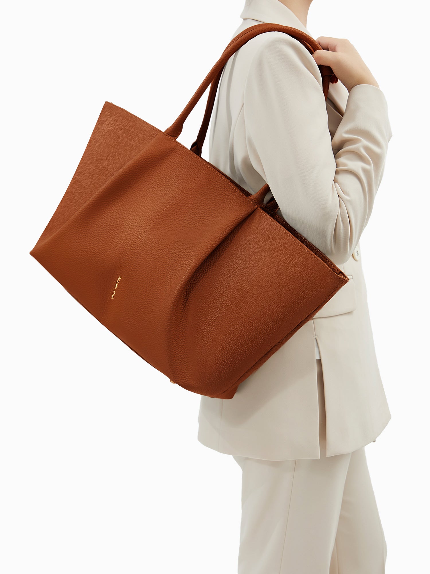 Model carrying the Victoria Hyde Ada Brown business laptop bag in brown as a shoulder bag, made of stylish, ergonomic vegan leather.