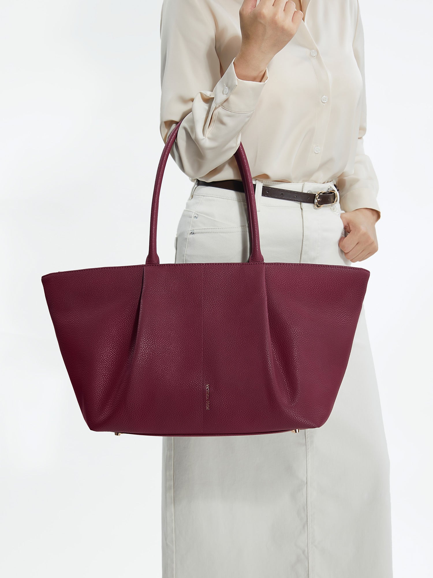 Professional woman carrying the Victoria Hyde Ada Red laptop handbag, elegant vegan leather design with 16-inch laptop compartment for office work.