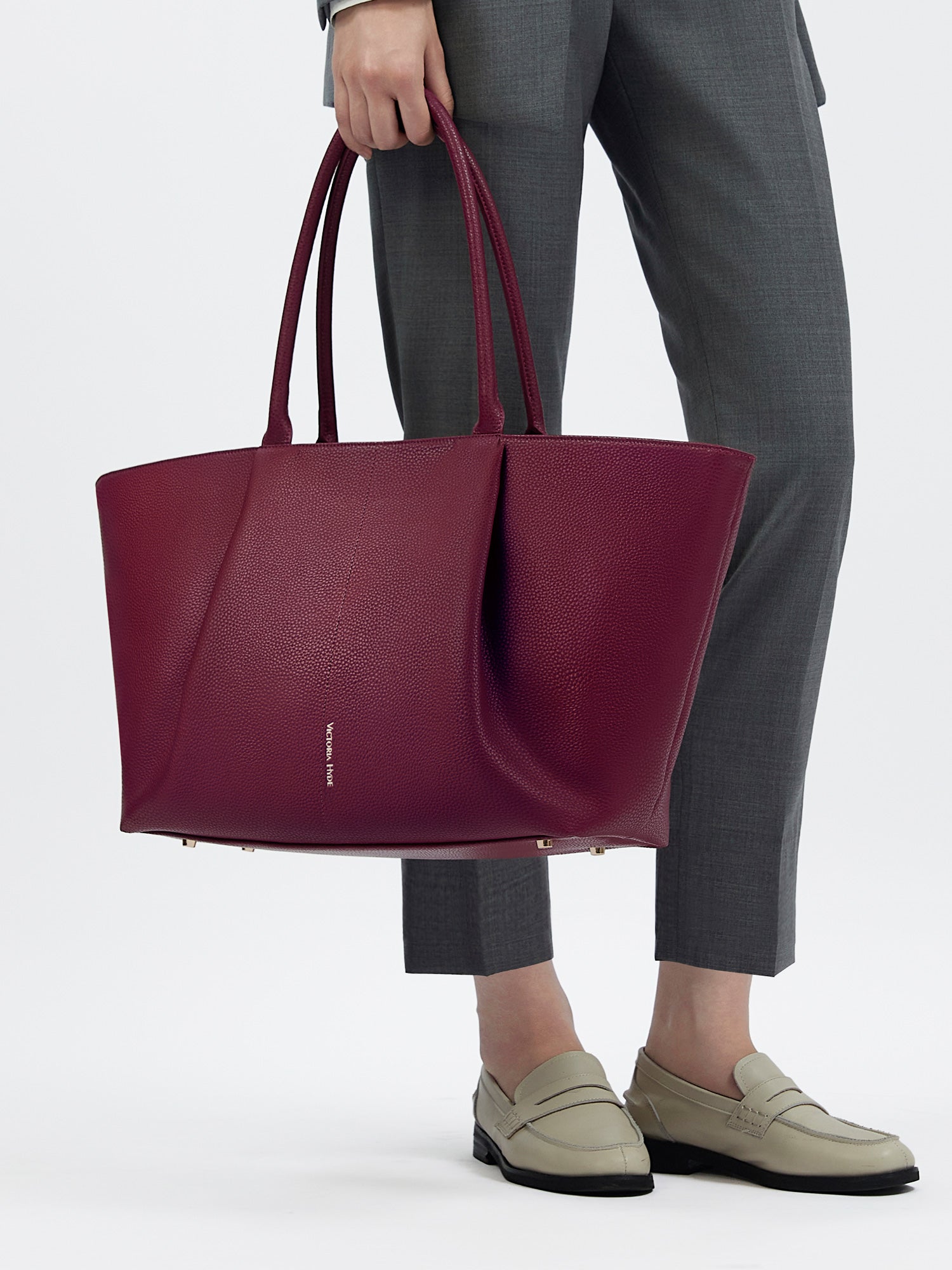 Professional woman carrying the Victoria Hyde Ada Red laptop handbag, elegant vegan leather design with 16-inch laptop compartment for office work.