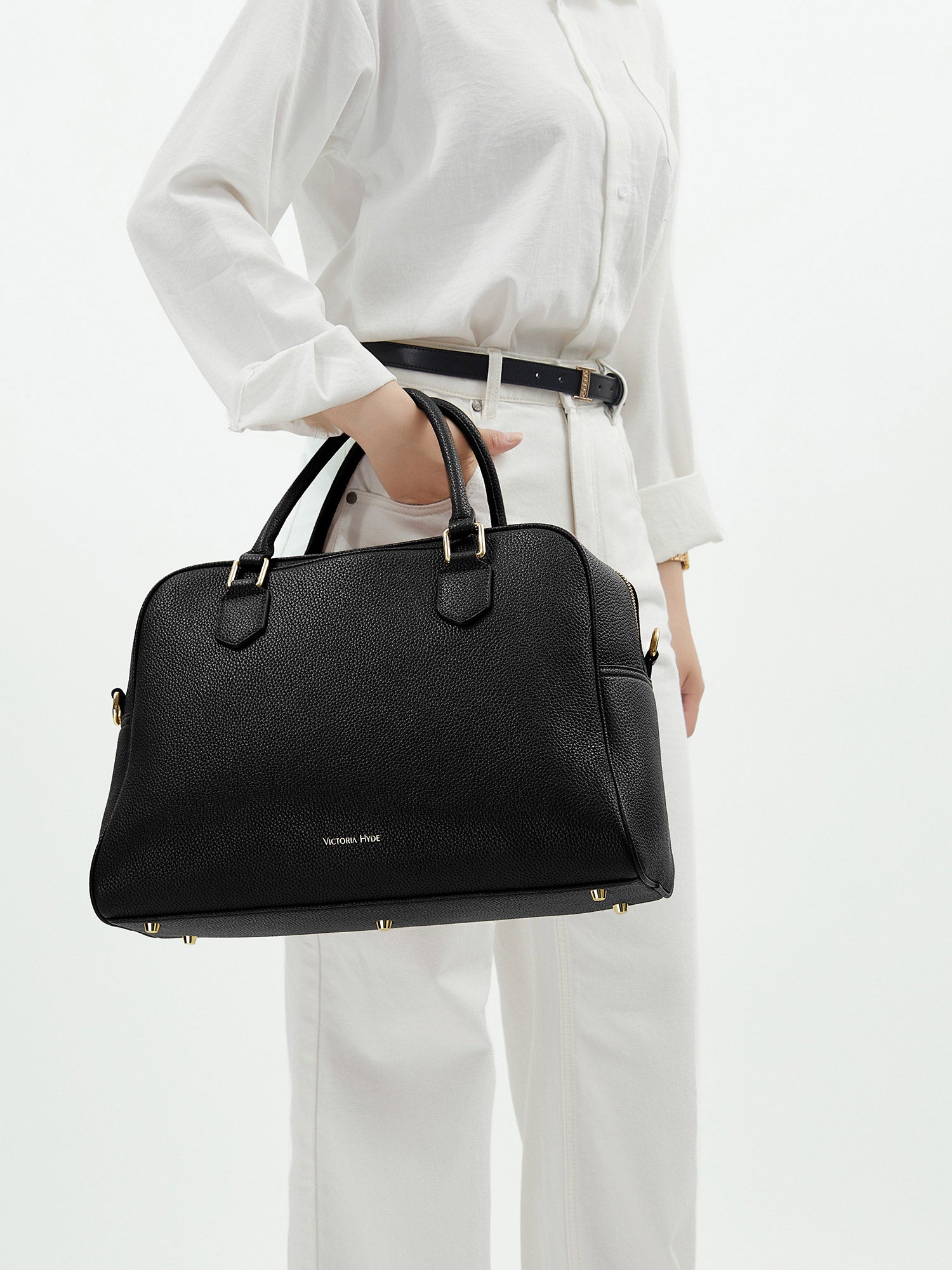 Professional woman carrying the Victoria Hyde Amal black laptop handbag, elegant vegan leather design with 14-inch laptop compartment for office work.