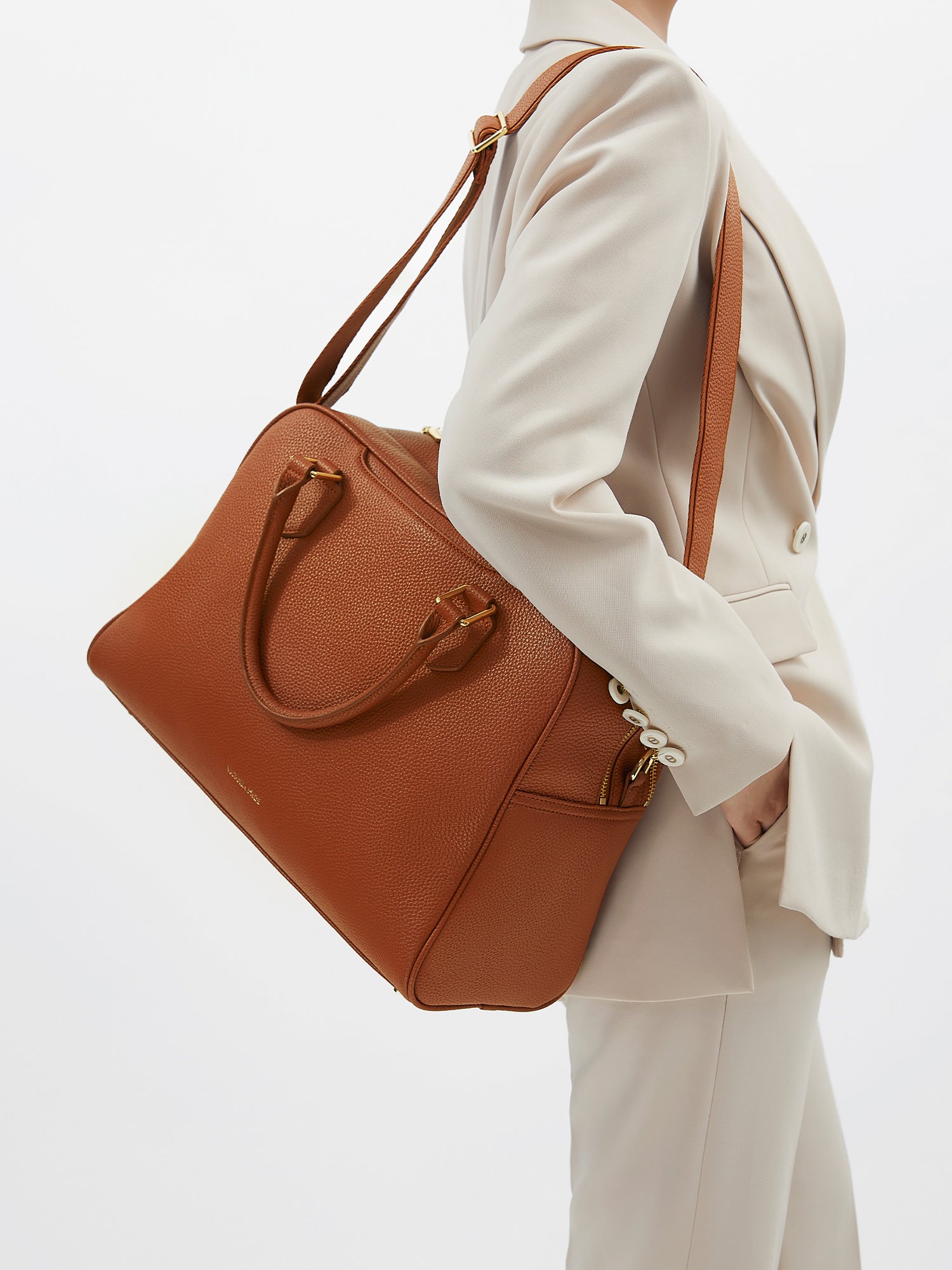 Model carrying the Victoria Hyde Amal 3-in-1 convertible laptop bag in brown as a shoulder bag, made of stylish, ergonomic vegan leather.