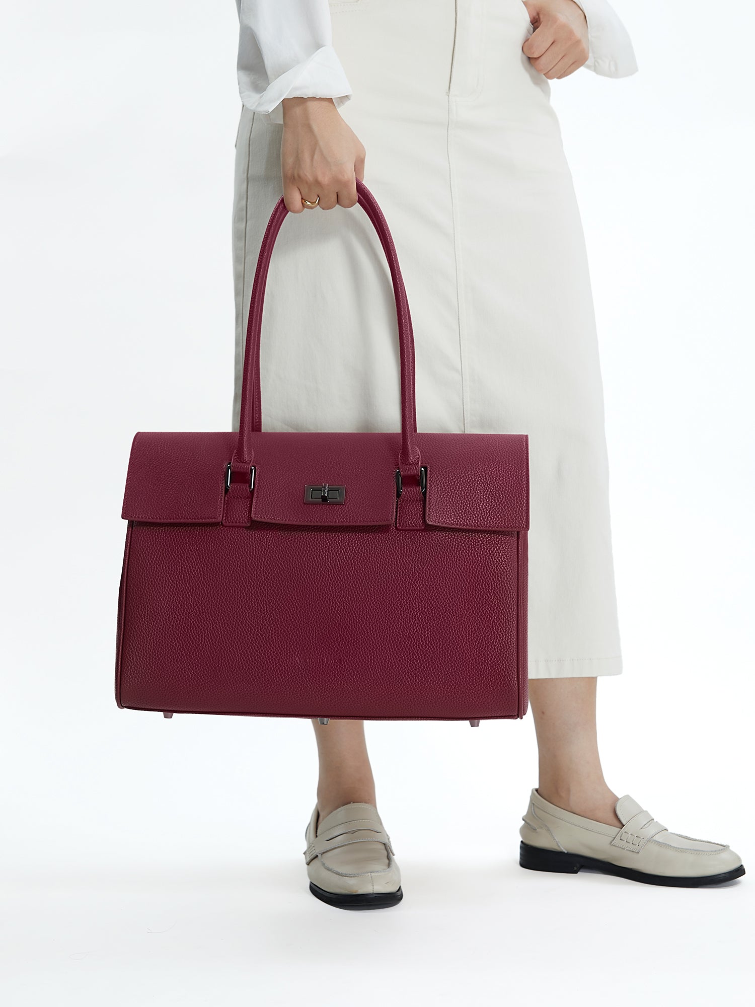 Professional woman carrying the Victoria Hyde Jolene winered laptop handbag, elegant vegan leather design with 16-inch laptop compartment for office work.