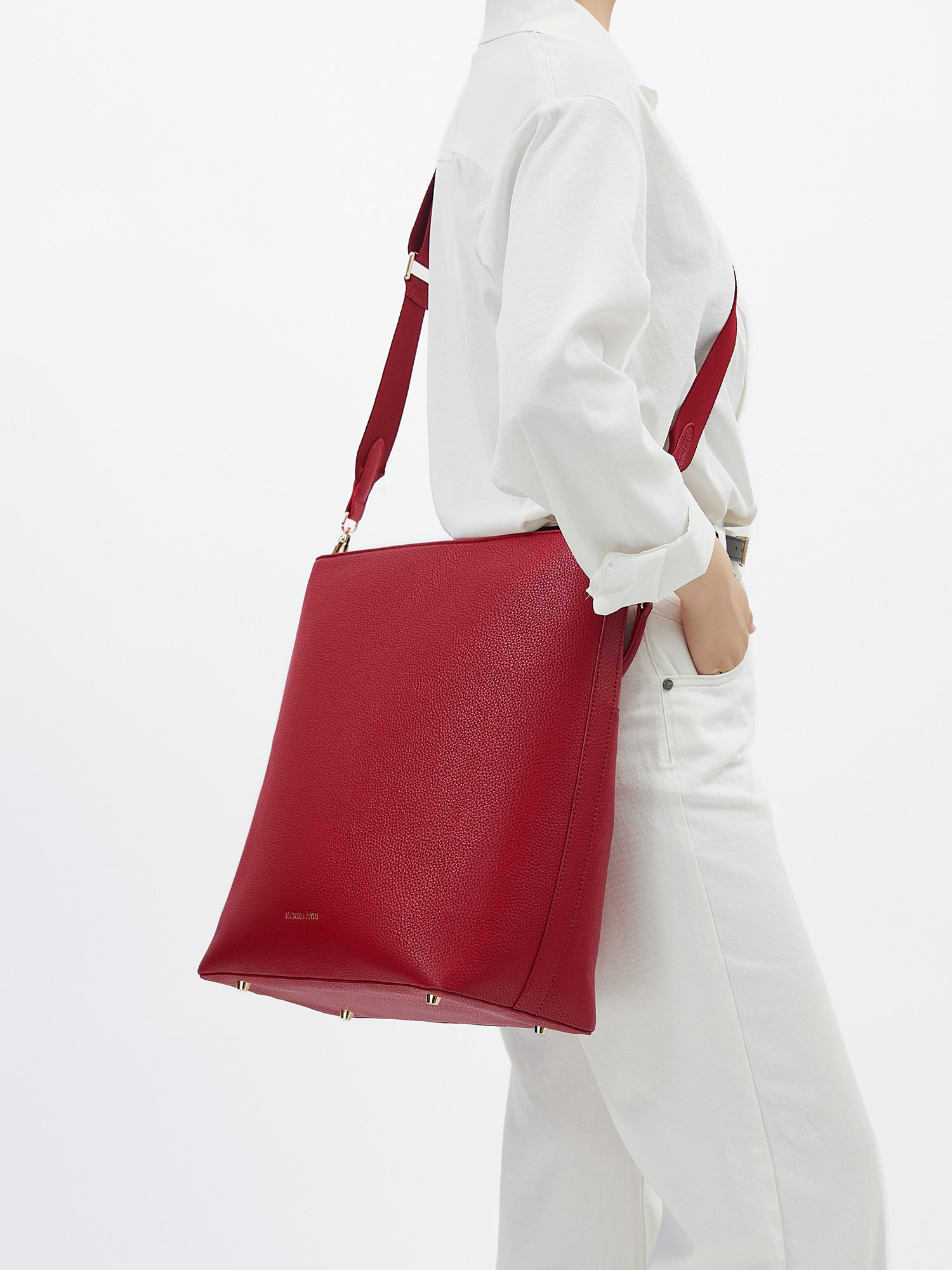 Model carrying the Victoria Hyde Kloey business laptop bag in granatrot as a shoulder bag, made of stylish, ergonomic vegan leather.
