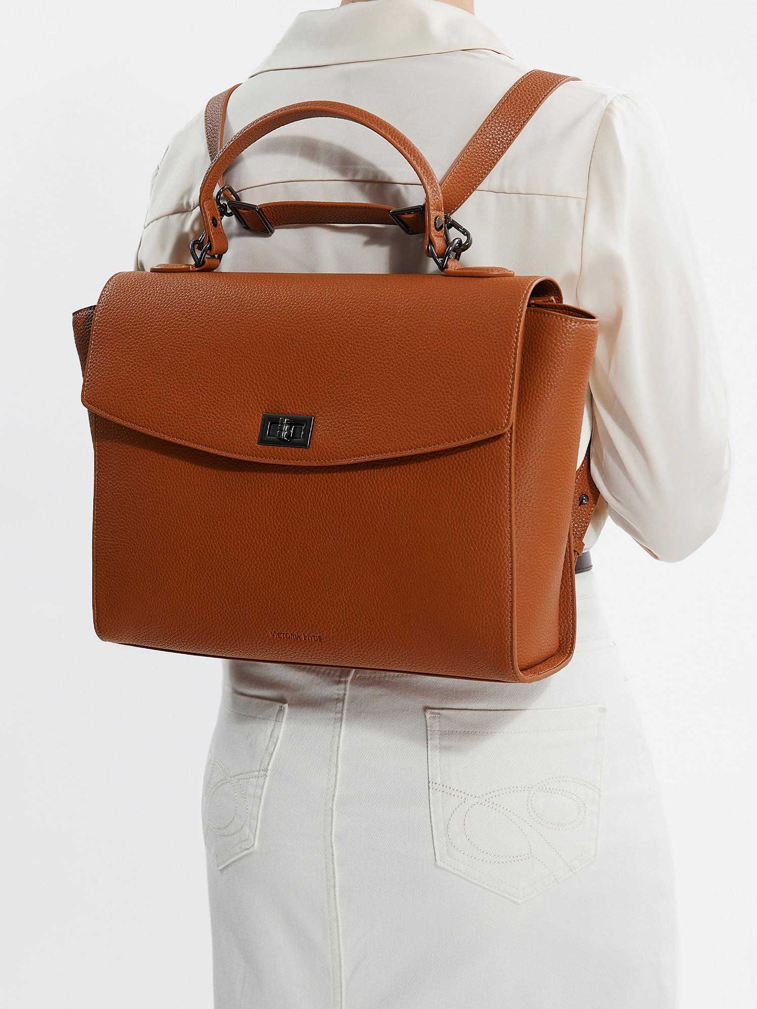 Model wearing Victoria Hyde Potter 2-in-1 braun laptop backpack, styled as a chic and ergonomic shoulder bag for professional commuters.