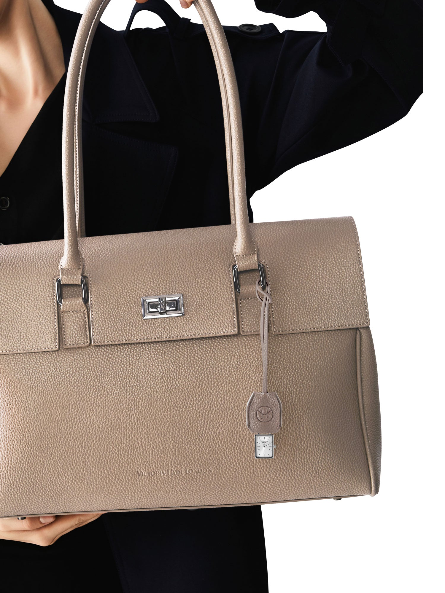 Victoria Hyde nude bag charm with watch and chain. Minimalist design with logo and flag symbol. Timeless accessory, 185mm chain length. Elegant functionality.