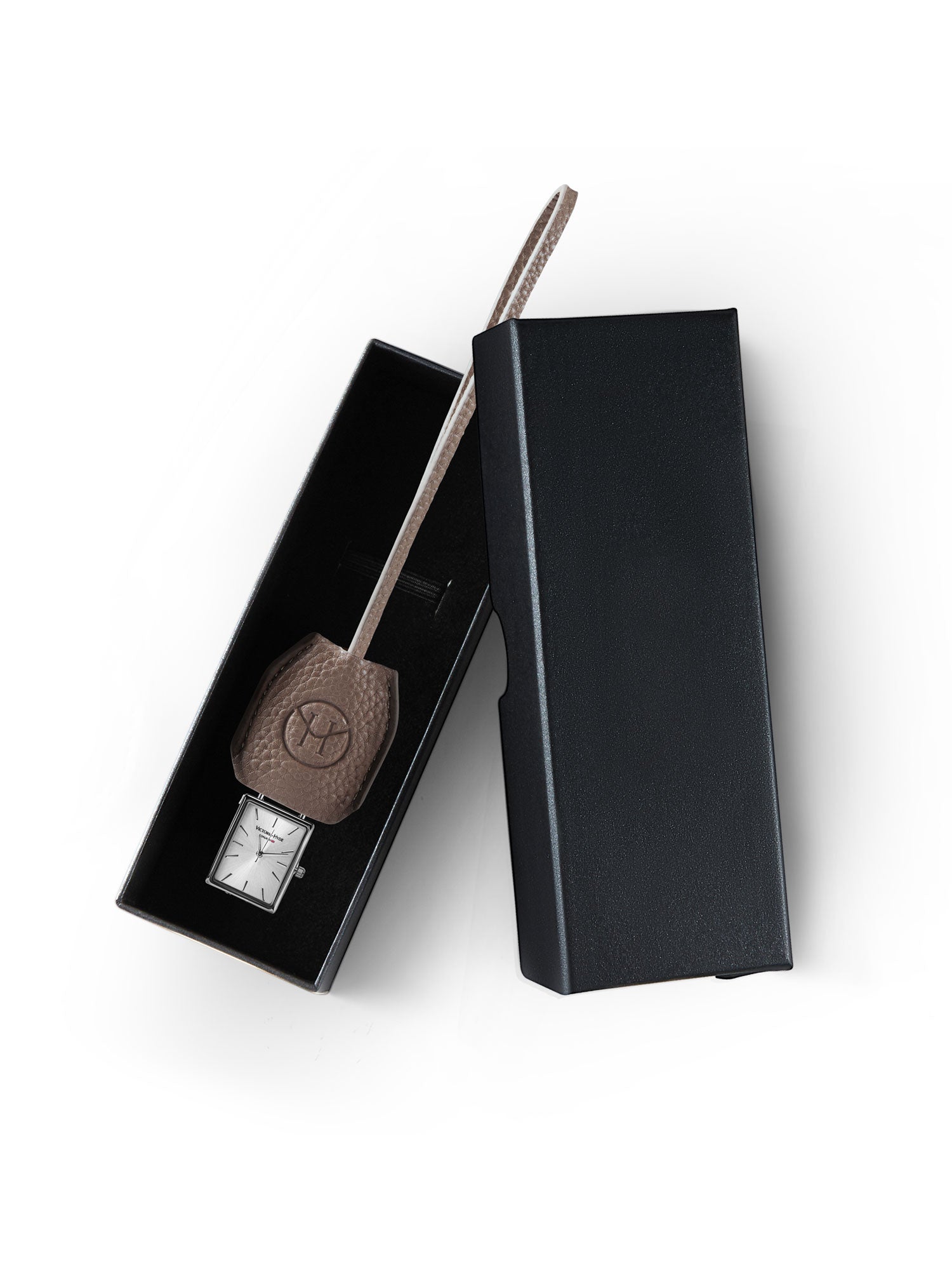 Victoria Hyde nude bag charm with watch and chain. Minimalist design with logo and flag symbol. Timeless accessory, 185mm chain length. Elegant functionality.