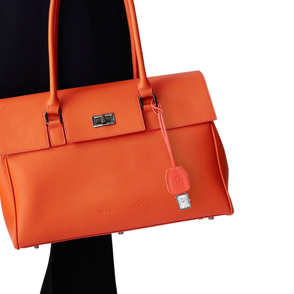 Victoria Hyde orange watch-shaped bag charm with chain. Minimalist design, subtle elegance, functional accessory. Pendant size 40x47 mm. Perfect for timeless style.
