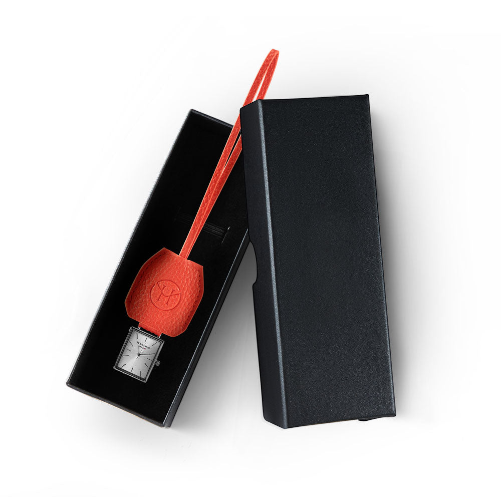Victoria Hyde orange watch-shaped bag charm with chain. Minimalist design, subtle elegance, functional accessory. Pendant size 40x47 mm. Perfect for timeless style.