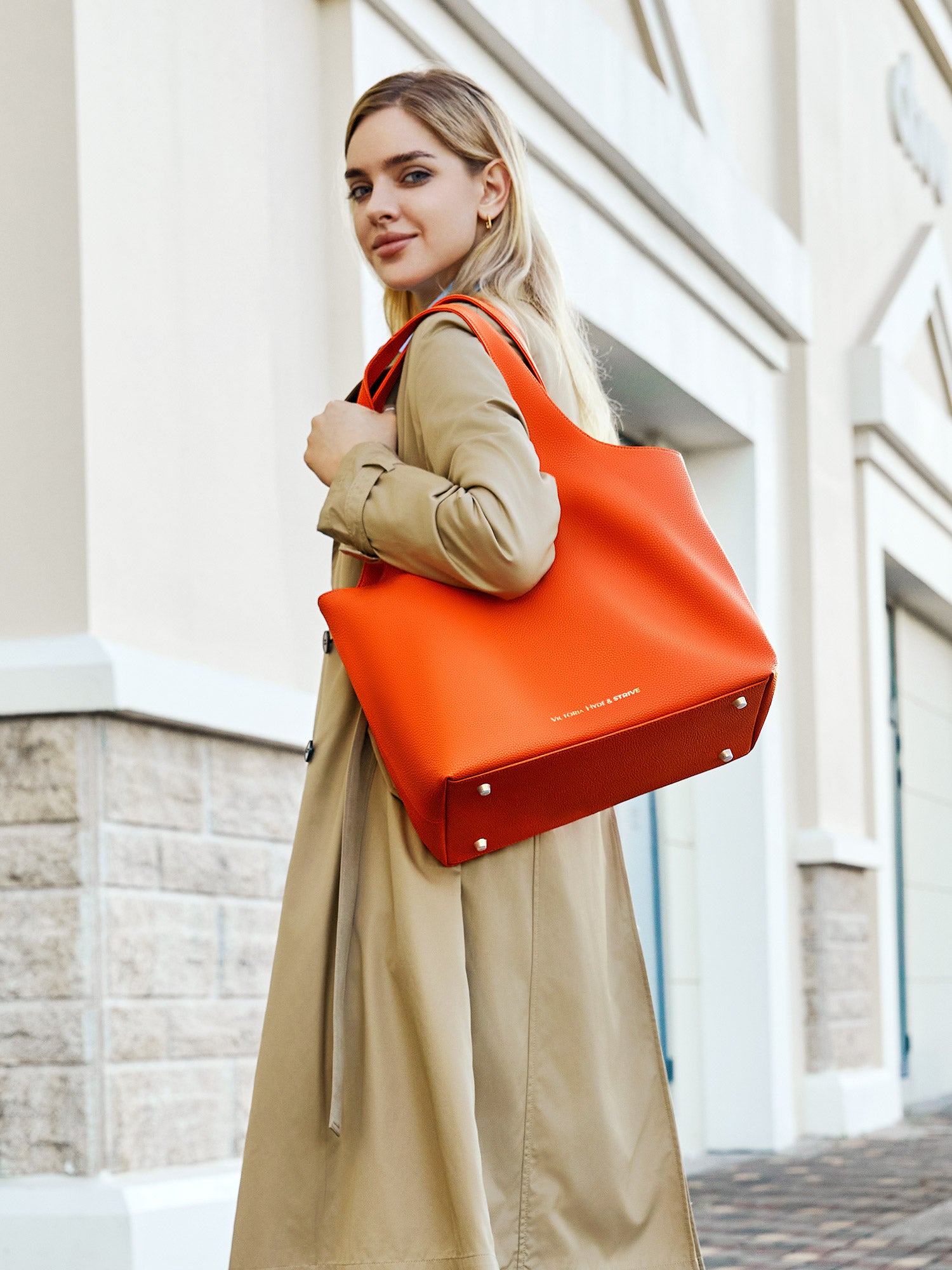 Victoria Hyde Strive Collection orange work bag with thoughtful interior pockets, removable laptop compartment, zippered back with trolley strap, durable microfiber leather, sustainable RPET lining, scratch-resistant & water-repellent. Ideal for professionals.