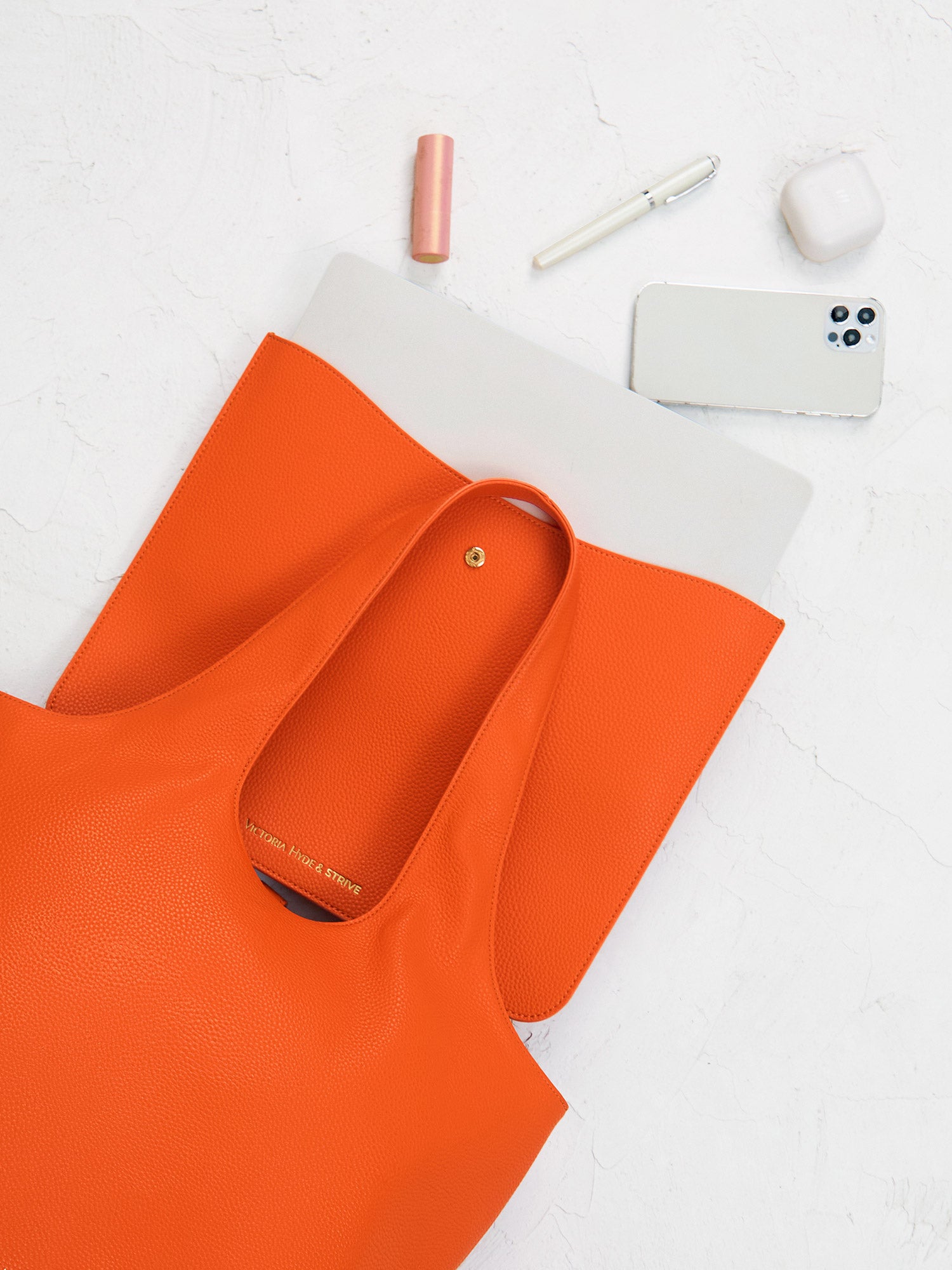 Victoria Hyde Strive Collection orange work bag with thoughtful interior pockets, removable laptop compartment, zippered back with trolley strap, durable microfiber leather, sustainable RPET lining, scratch-resistant & water-repellent. Ideal for professionals.