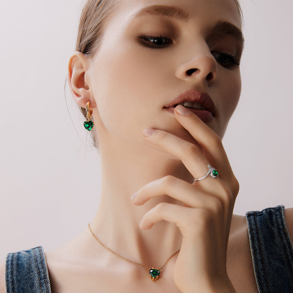 Victoria Hyde London heart-shaped jewelry set: necklace and earrings, light gold with deep green stones. Elegant, luxurious accessory for a refined look.