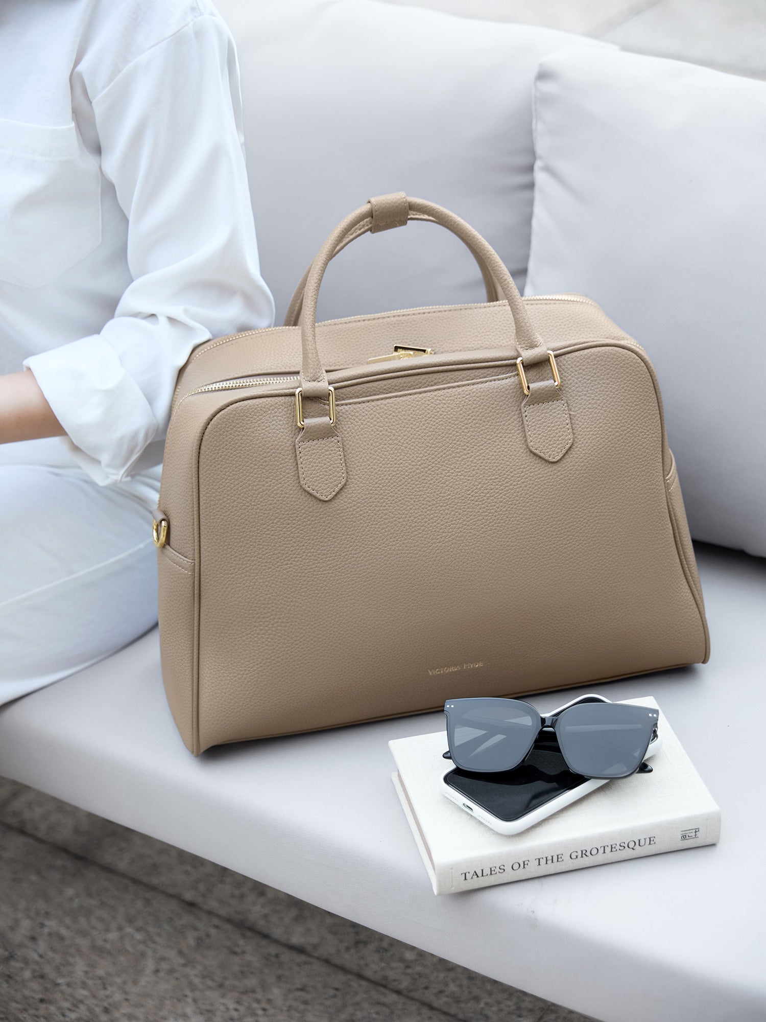 Victoria Hyde Amal 3-in-1 bag in nude vegan leather, styled as a chic handbag next to personal items, ideal for 14-inch laptops and professional commuters.