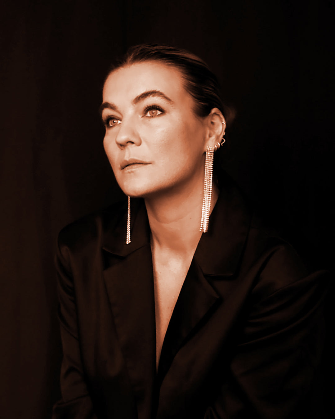 Professionelles Porträt von Dajana Eder, Gründerin von WÆRE bodysuits, im schwarzen Satin-Blazer mit langen Ohrringen, vorgestellt als wegweisende Technologin und Expertin für Personal Branding.