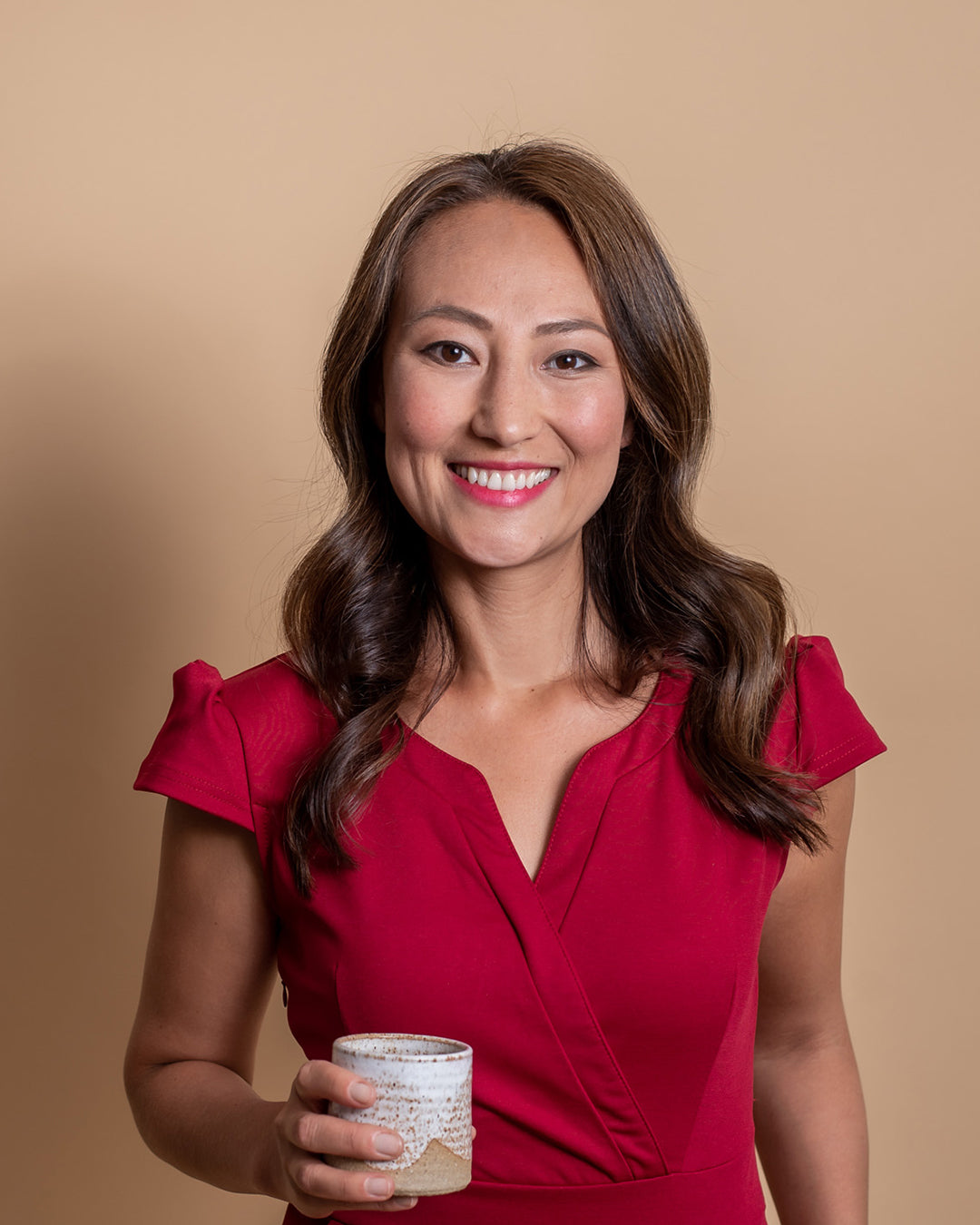 Professionelles Porträt von Elnura Ashimova, COO bei 2hearts, im roten Kleid mit einem Glas in der Hand, für einen Beitrag über die Förderung junger Tech-Talente mit Migrationshintergrund.