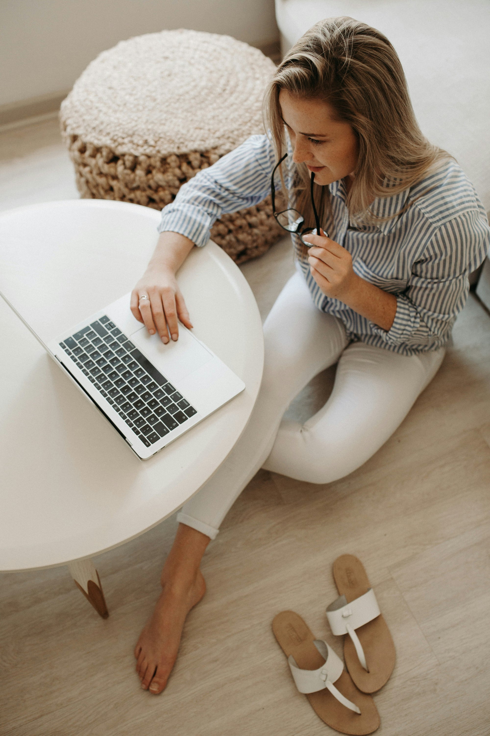 Eine professionelle Frau arbeitet an einem Laptop an einem hellen Tisch und verkörpert den "New Work"-Lifestyle von Victoria Hyde London. Sie wirkt konzentriert und entspannt, was modernes Work-Life-Blending und berufliche Unabhängigkeit repräsentiert. Dieses Bild unterstreicht das funktionale, stilvolle Design der VHL Business-Accessoires für die moderne Frau von heute.