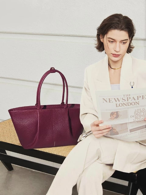 Woman placing a 16-inch laptop into a Victoria Hyde Ada red business tote bag, highlighting the spacious, organized interior for professional office use.