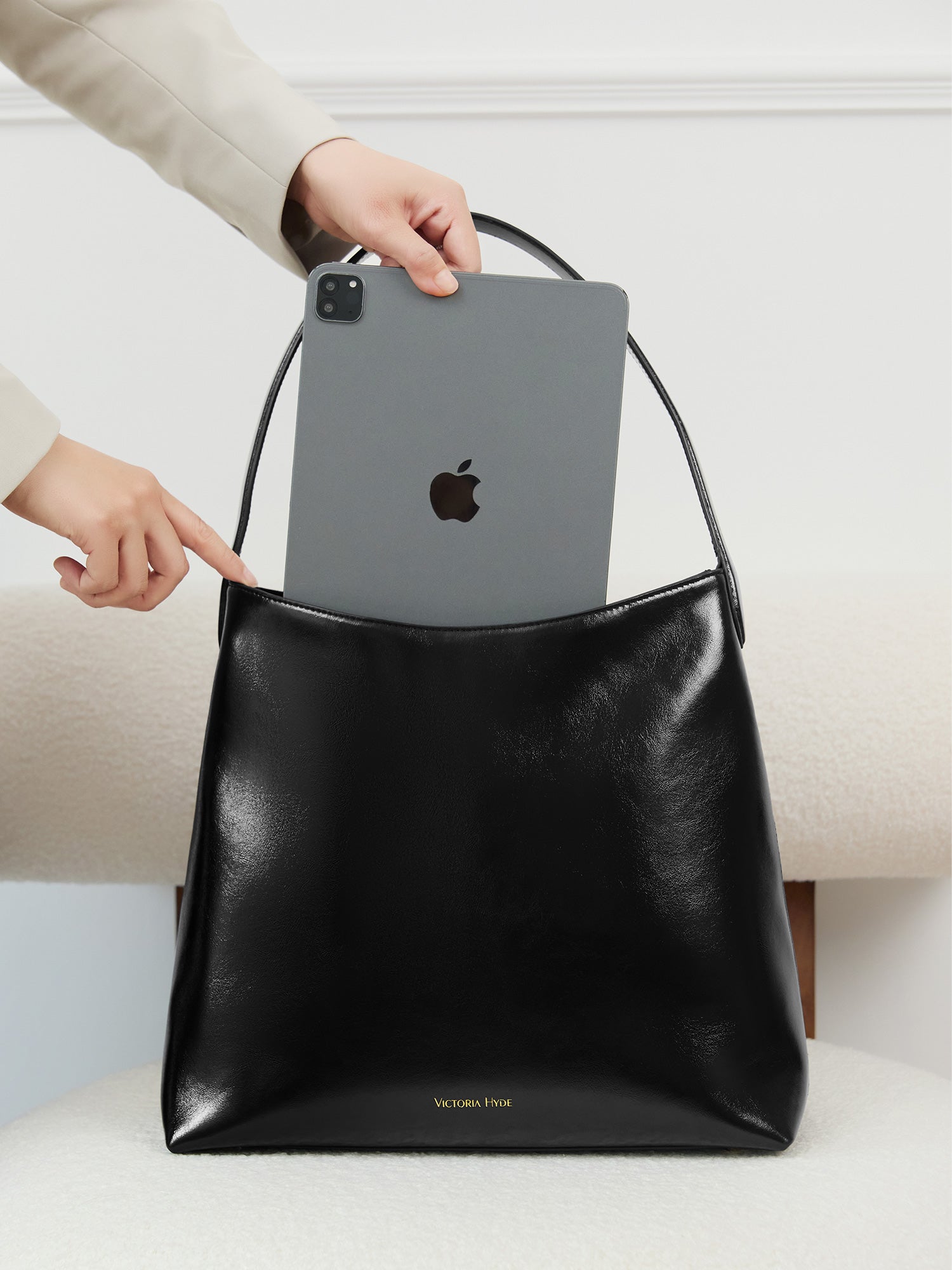 Victoria Hyde shoulder bag, microfiber leather, recycled lining. Padded sunglasses compartment, trolley strap, light gold hardware. “Love what you do” detail.