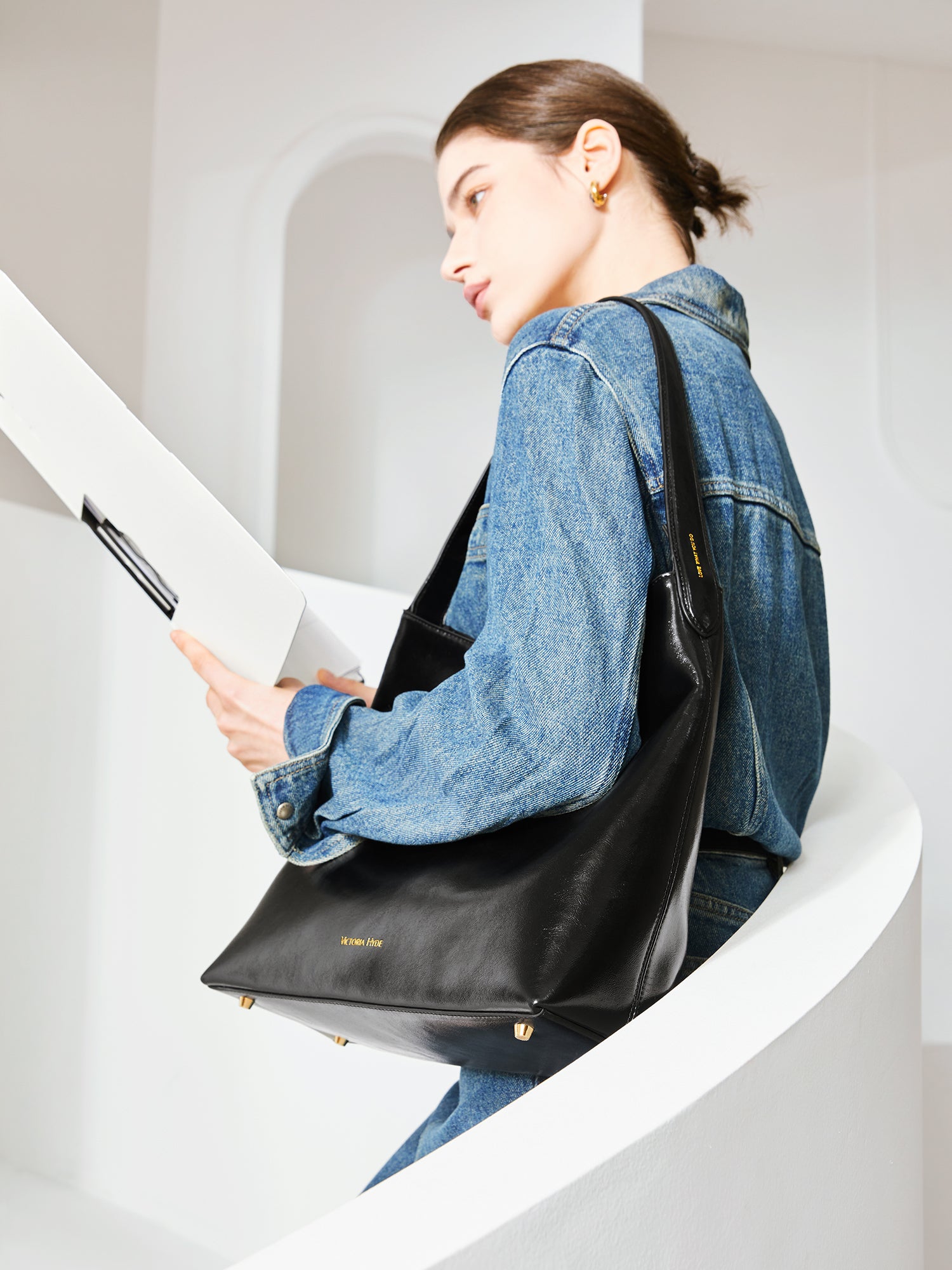 Victoria Hyde shoulder bag, microfiber leather, recycled lining. Padded sunglasses compartment, trolley strap, light gold hardware. “Love what you do” detail.