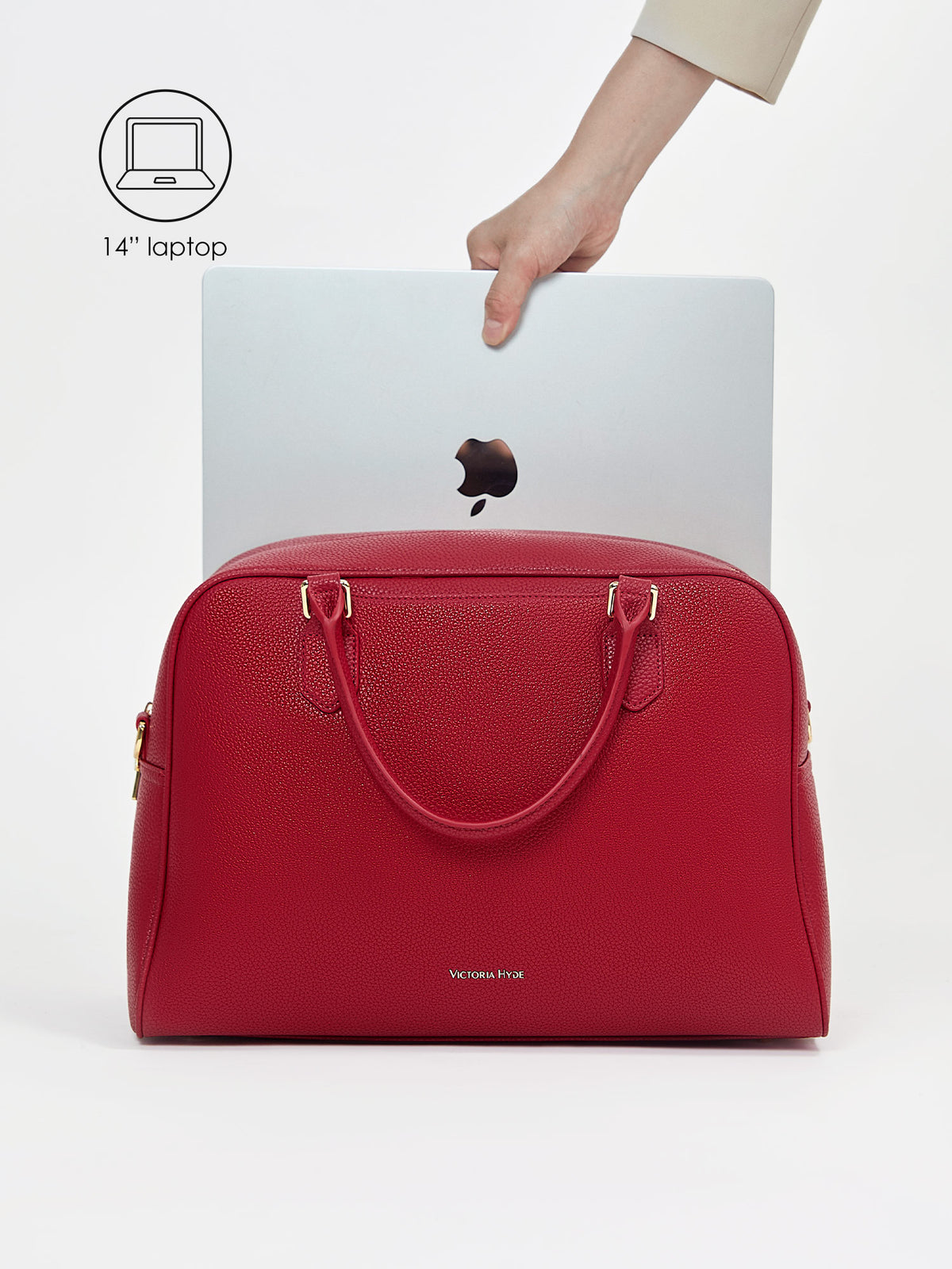 Placing a 14-inch laptop into the padded protective compartment of Victoria Hyde Amal garnet red bag