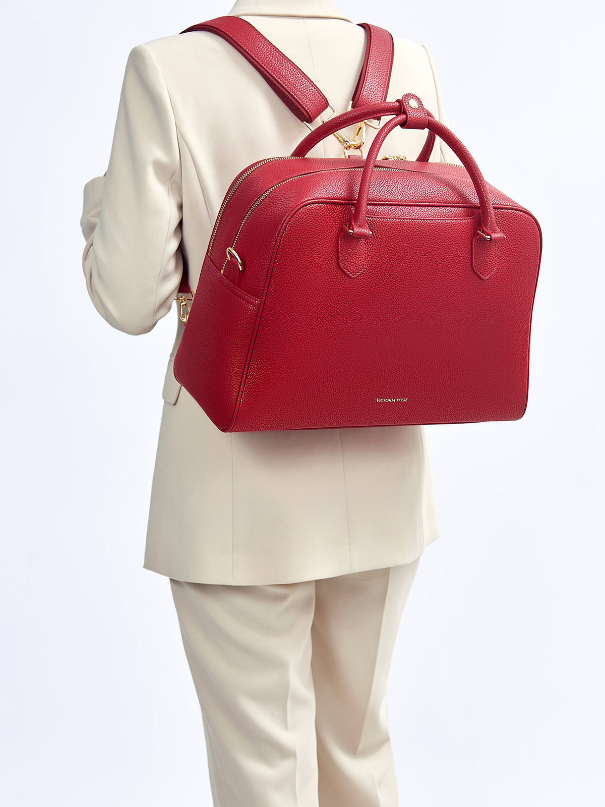 Model wearing Victoria Hyde Amal garnet red 3-in-1 convertible bag in backpack mode for ergonomic commute