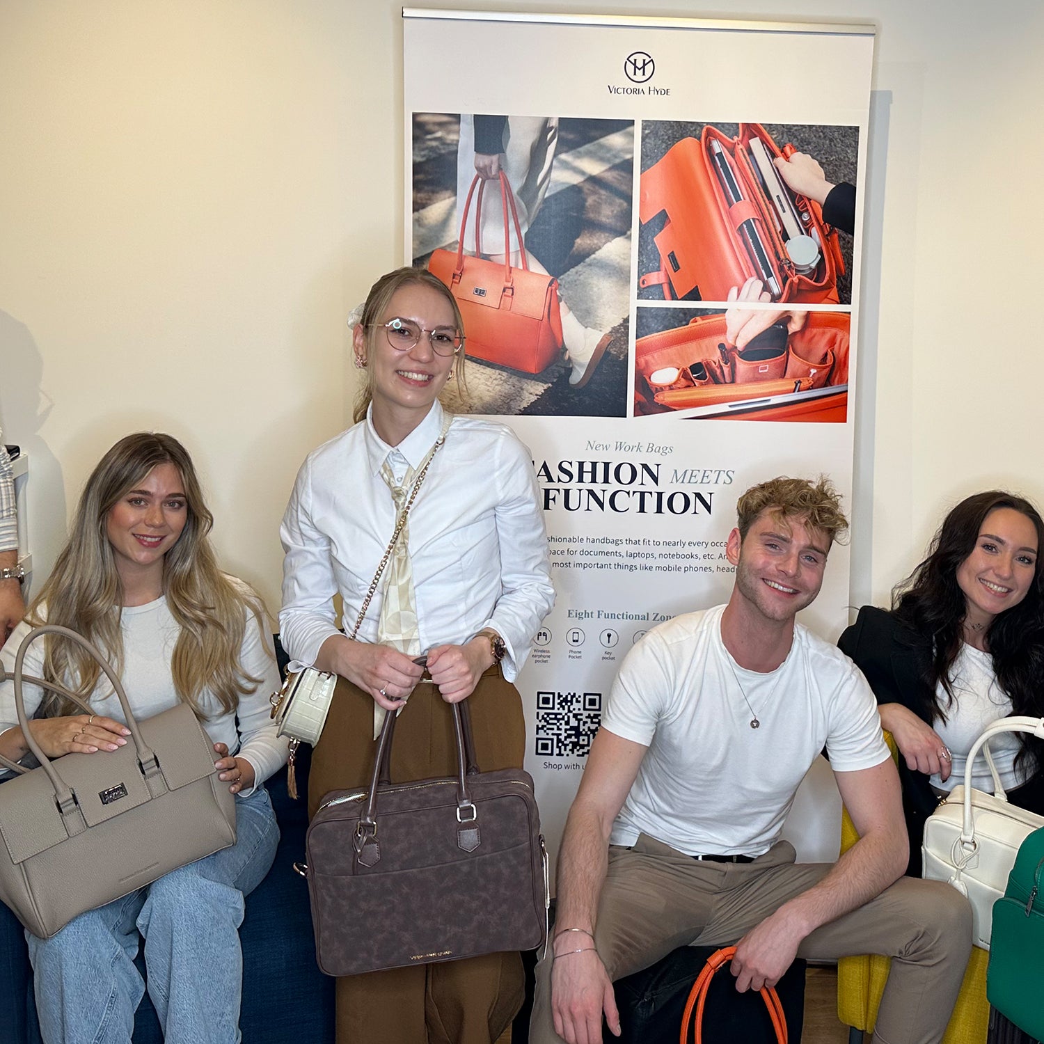 Eine Gruppe junger Berufstätiger posiert mit Victoria Hyde Laptoptaschen auf dem Creative Talk Event am 4. August 2025 vor einem Produktplakat.