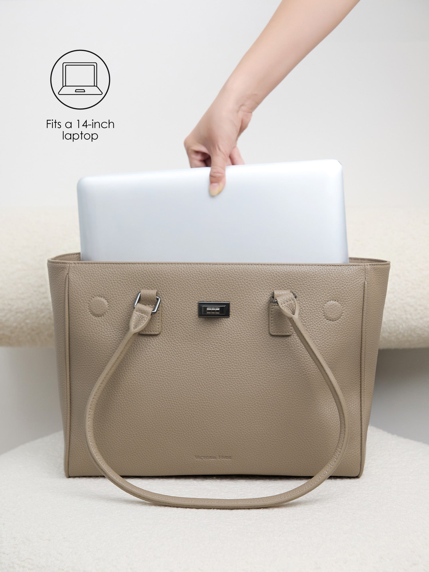 Placing a 14-inch laptop into the protective padded compartment of the Victoria Hyde Jolene Medium beige business bag