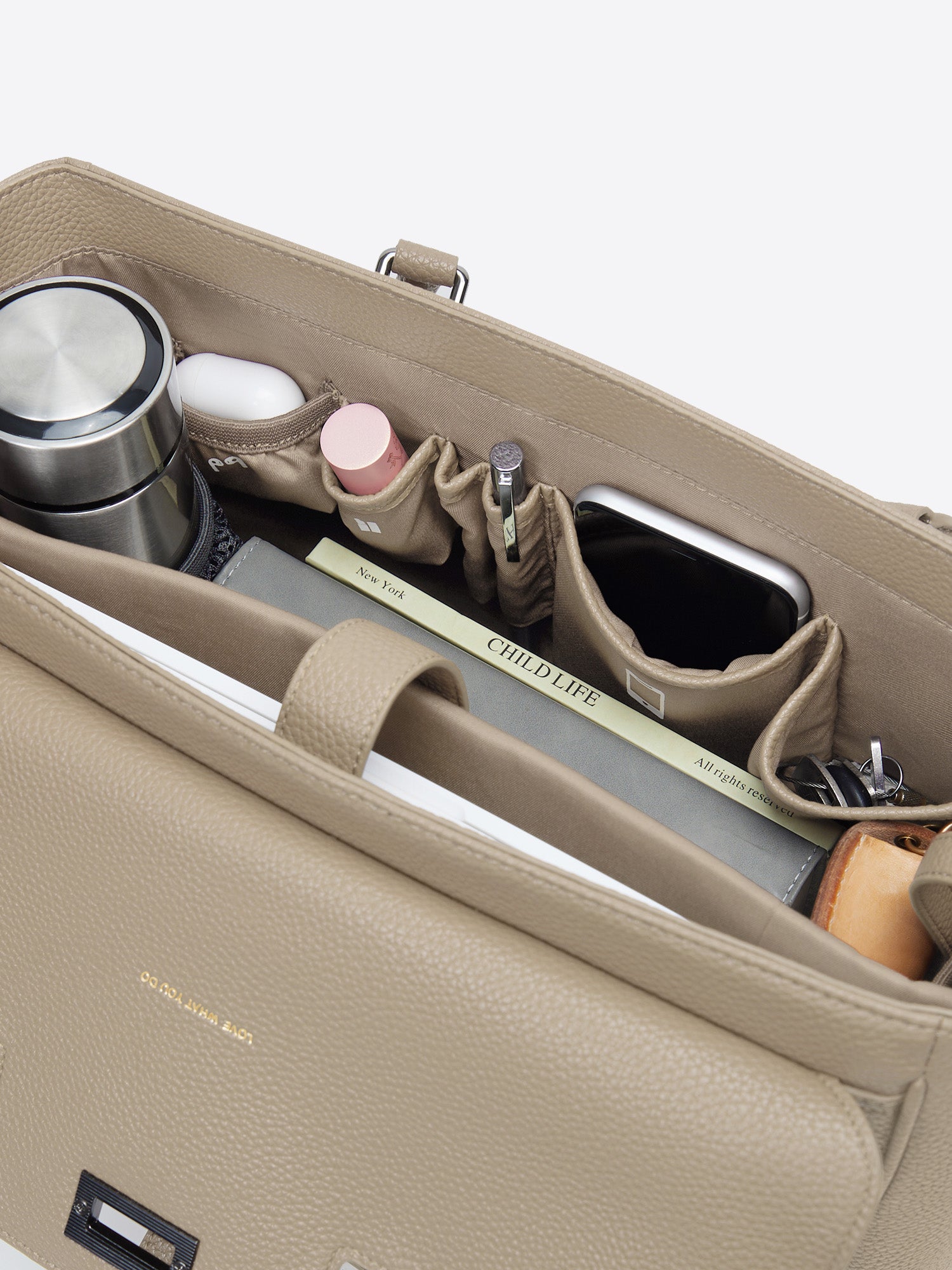 Organized interior top view of Jolene Medium beige business bag packed with water bottle mesh pocket, cosmetics, and notebook