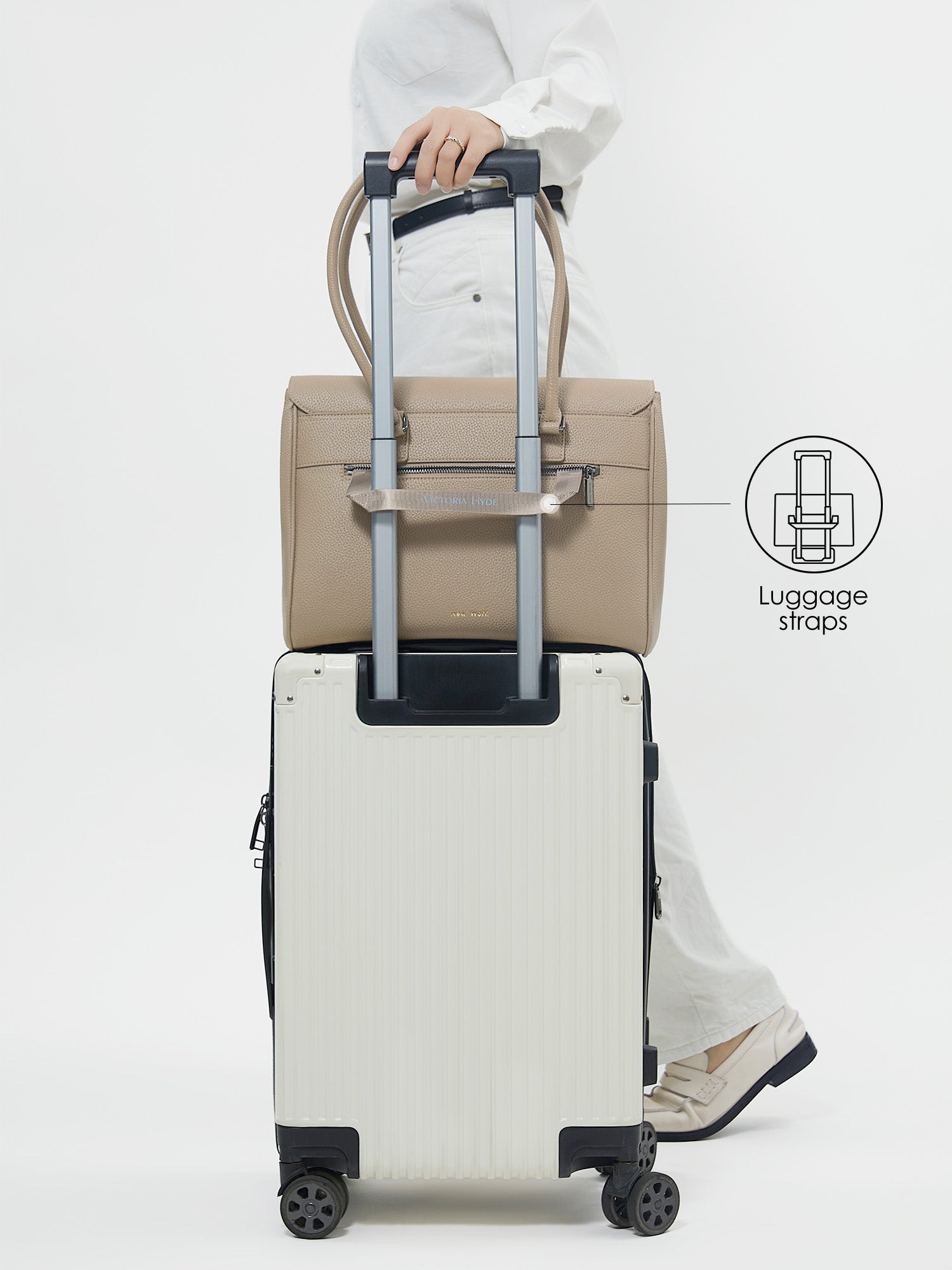 Back view of Victoria Hyde Jolene Medium beige business bag secured on a suitcase handle using the built-in luggage strap for travel