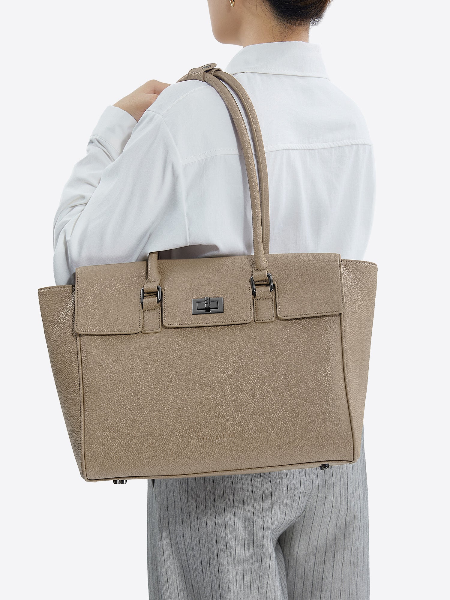 Side view of model carrying the beige Victoria Hyde Jolene Medium business bag and shoulder bag  for office work.