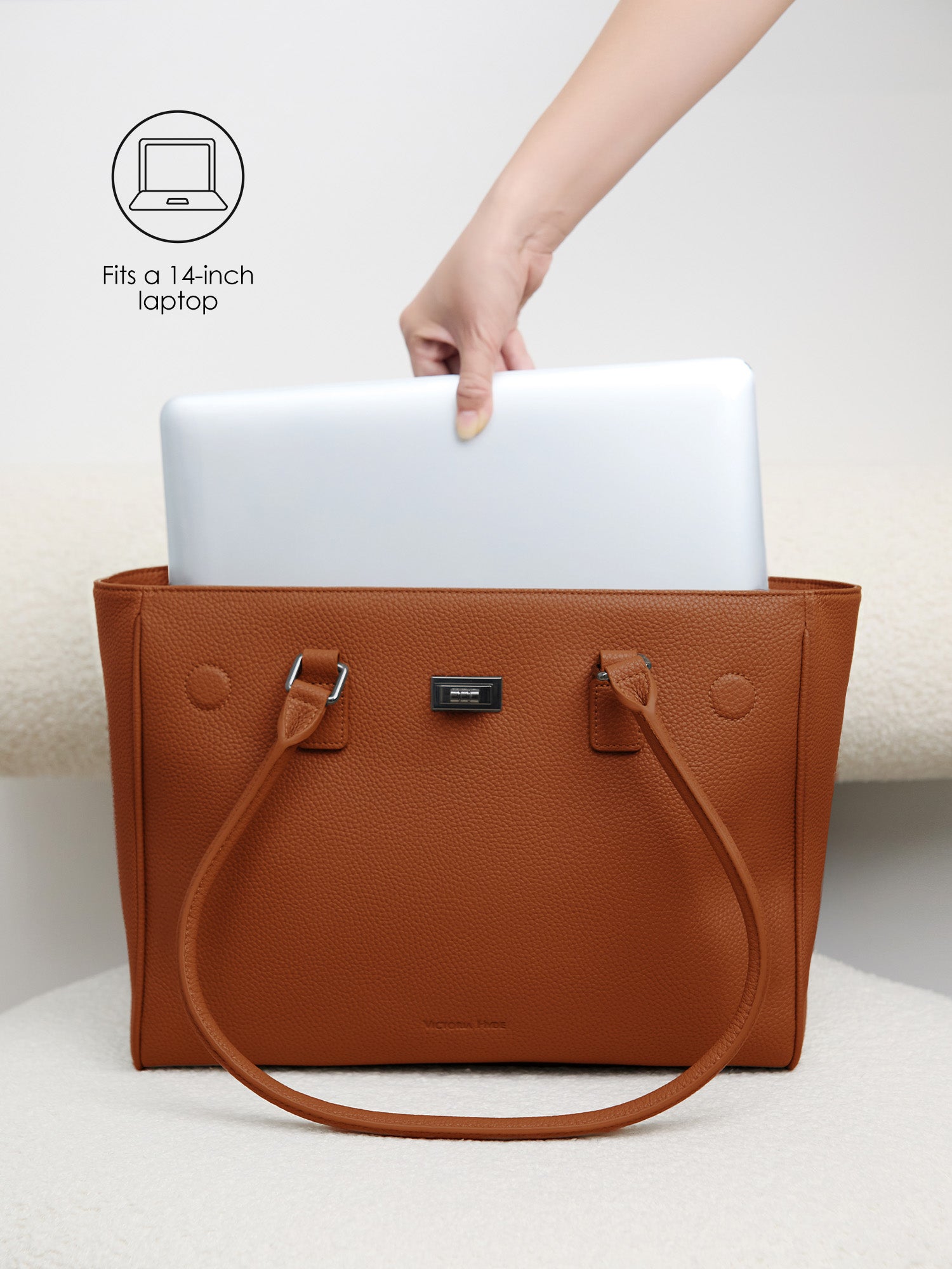 Placing a 14-inch laptop into the protective padded compartment of the Victoria Hyde Jolene Medium brown business bag
