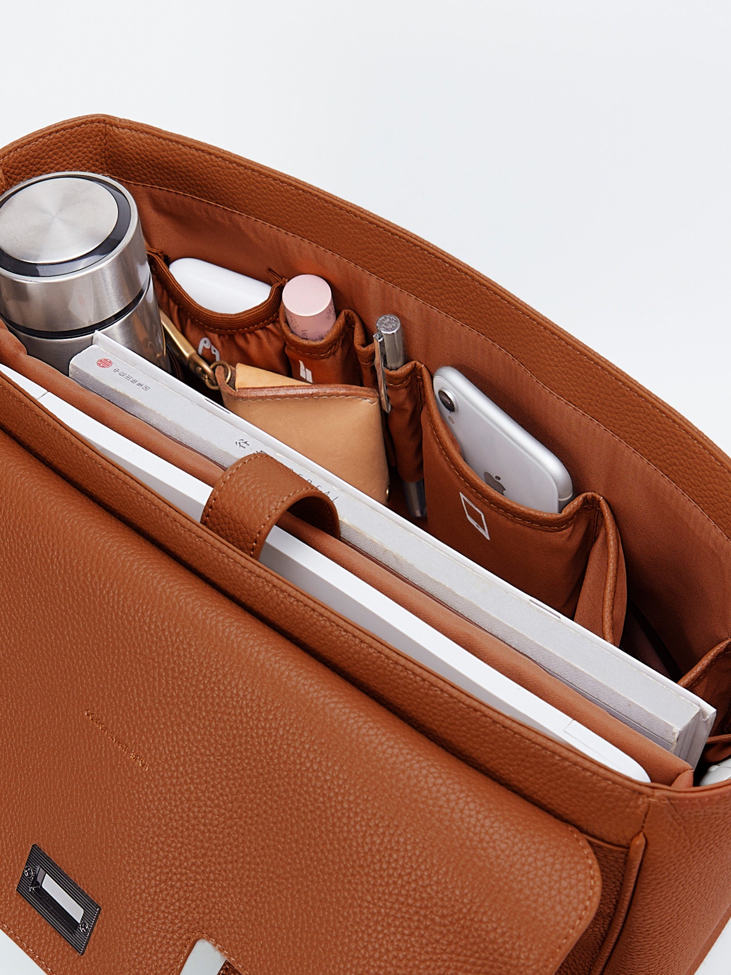 Organized interior top view of Jolene Medium brown business bag packed with water bottle mesh pocket, cosmetics, and notebook