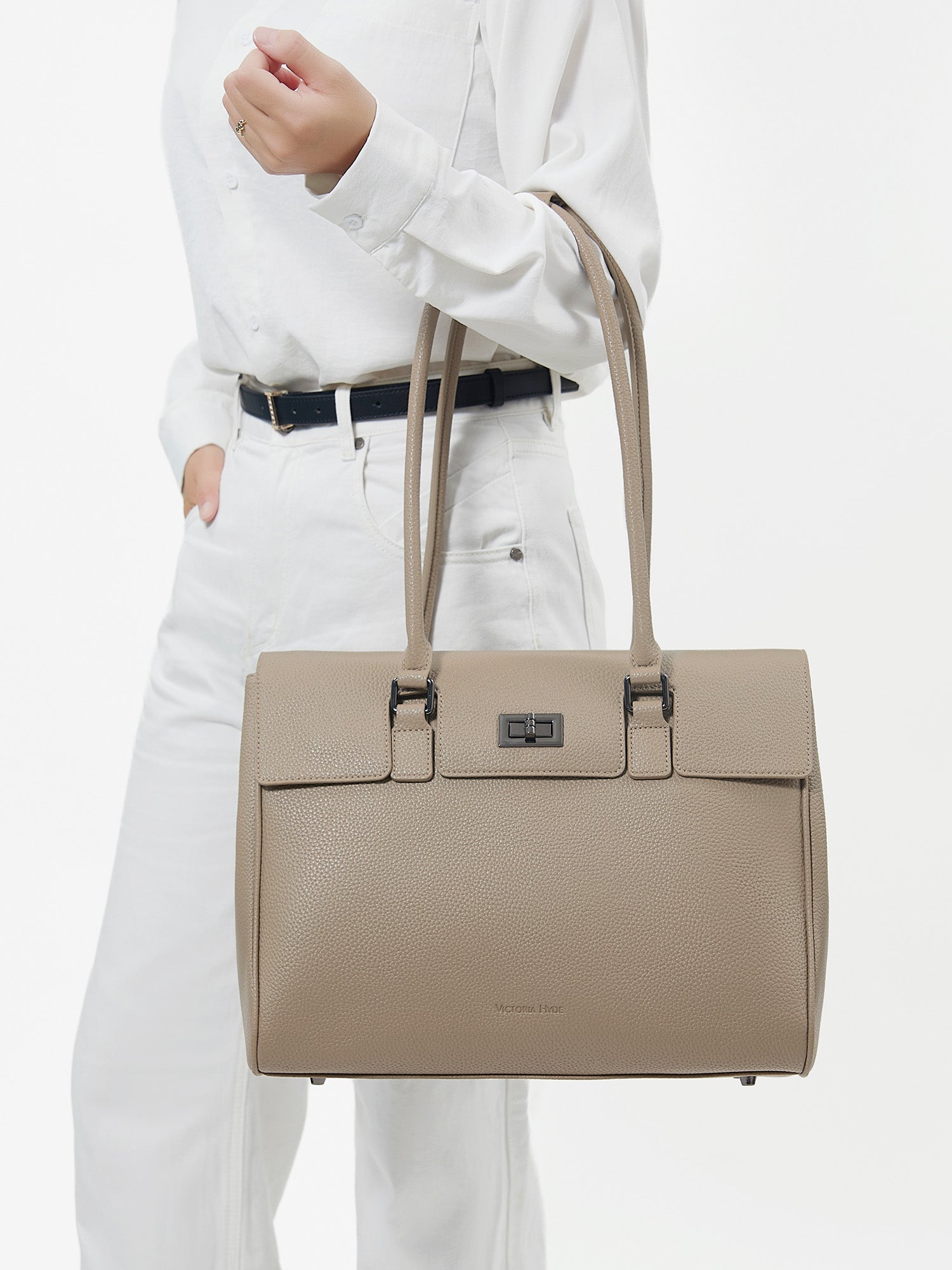 Professional woman carrying the Victoria Hyde Jolene Medium beige laptop handbag and business bag, elegant vegan leather design with 14-inch laptop compartment for office work.
