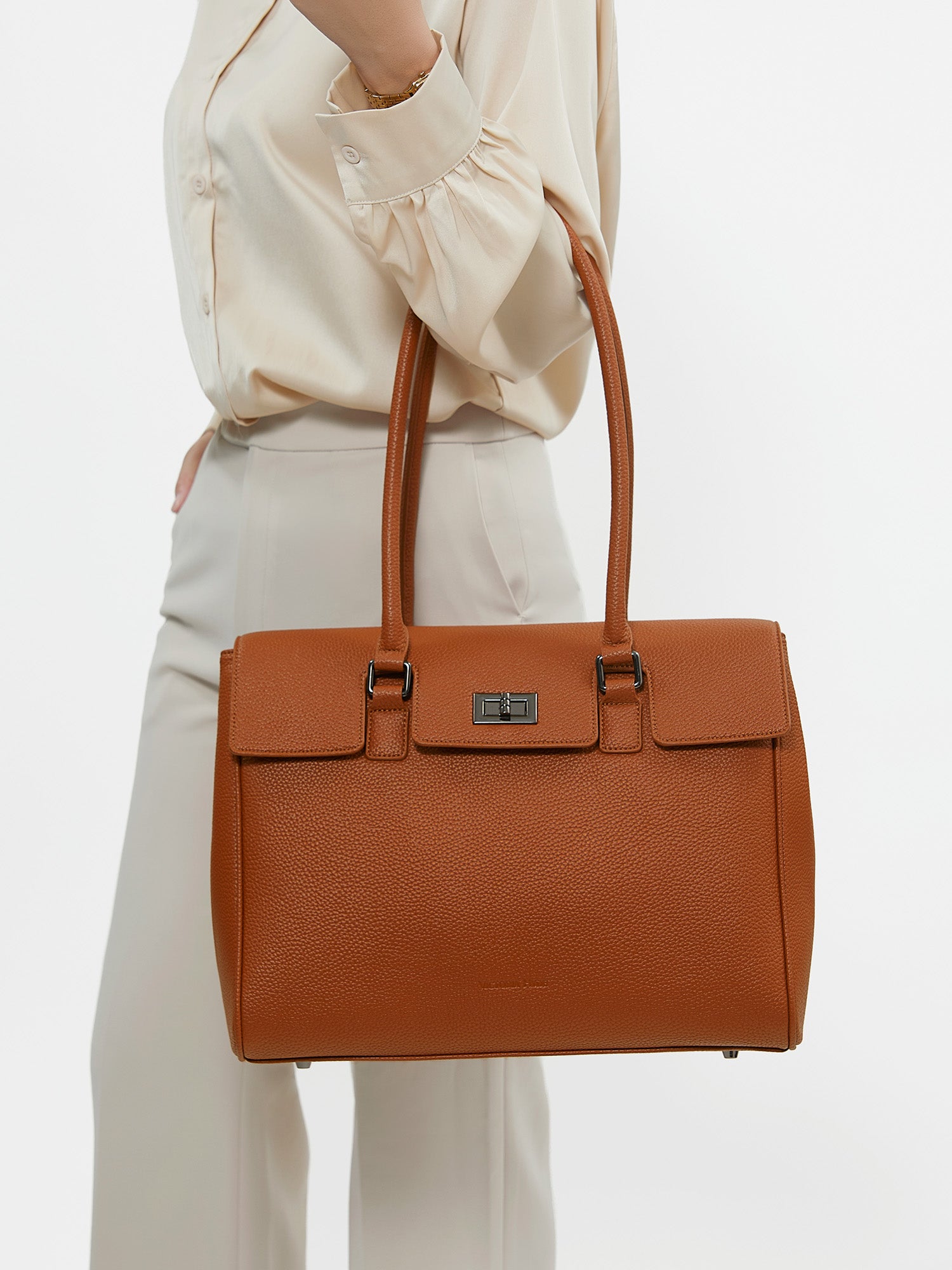 Professional woman carrying the Victoria Hyde Jolene Medium brown laptop handbag and business bag, elegant vegan leather design with 14-inch laptop compartment for office work.