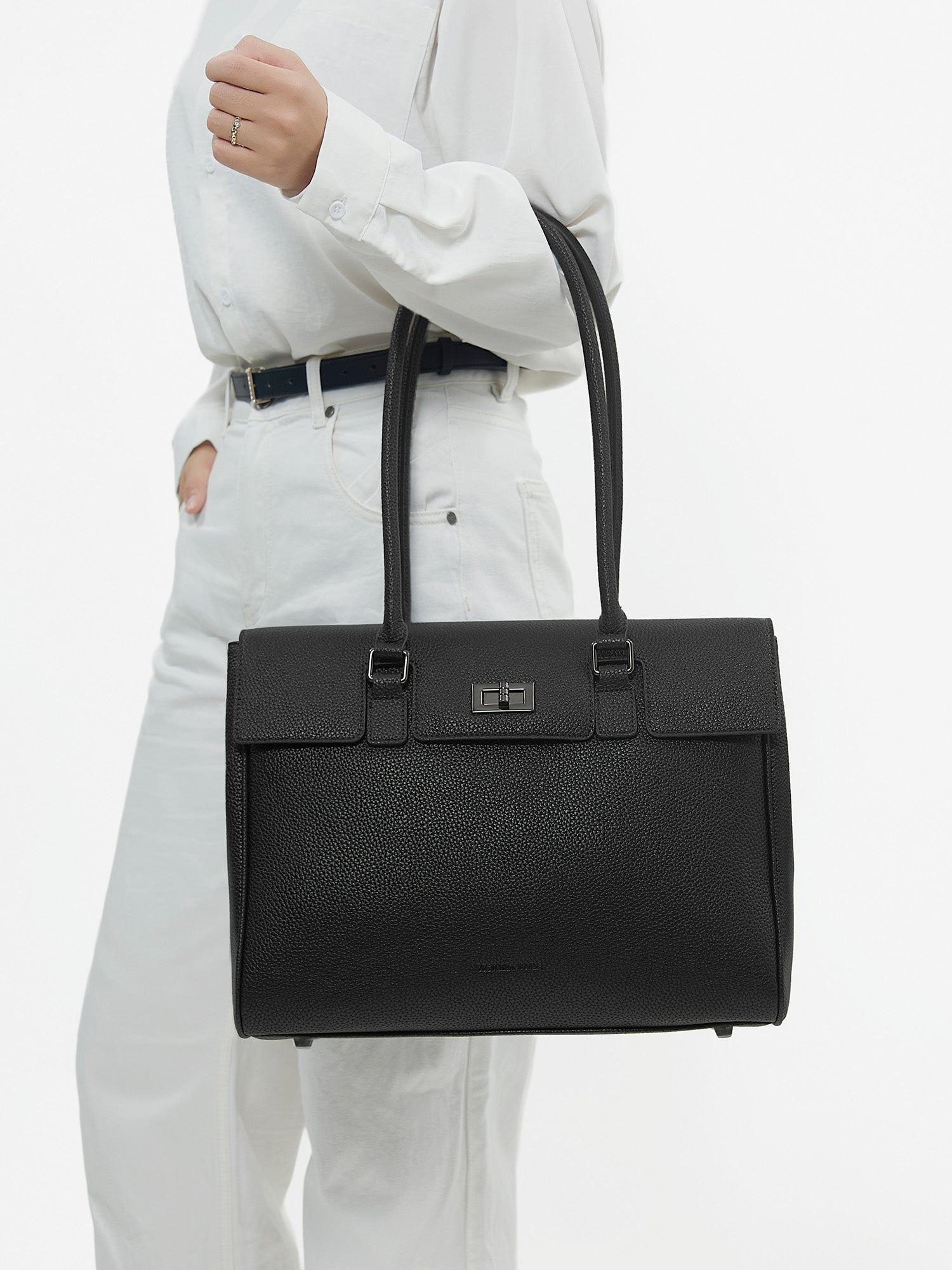 Professional woman carrying the Victoria Hyde Jolene Medium black laptop handbag and business bag, elegant vegan leather design with 14-inch laptop compartment for office work.