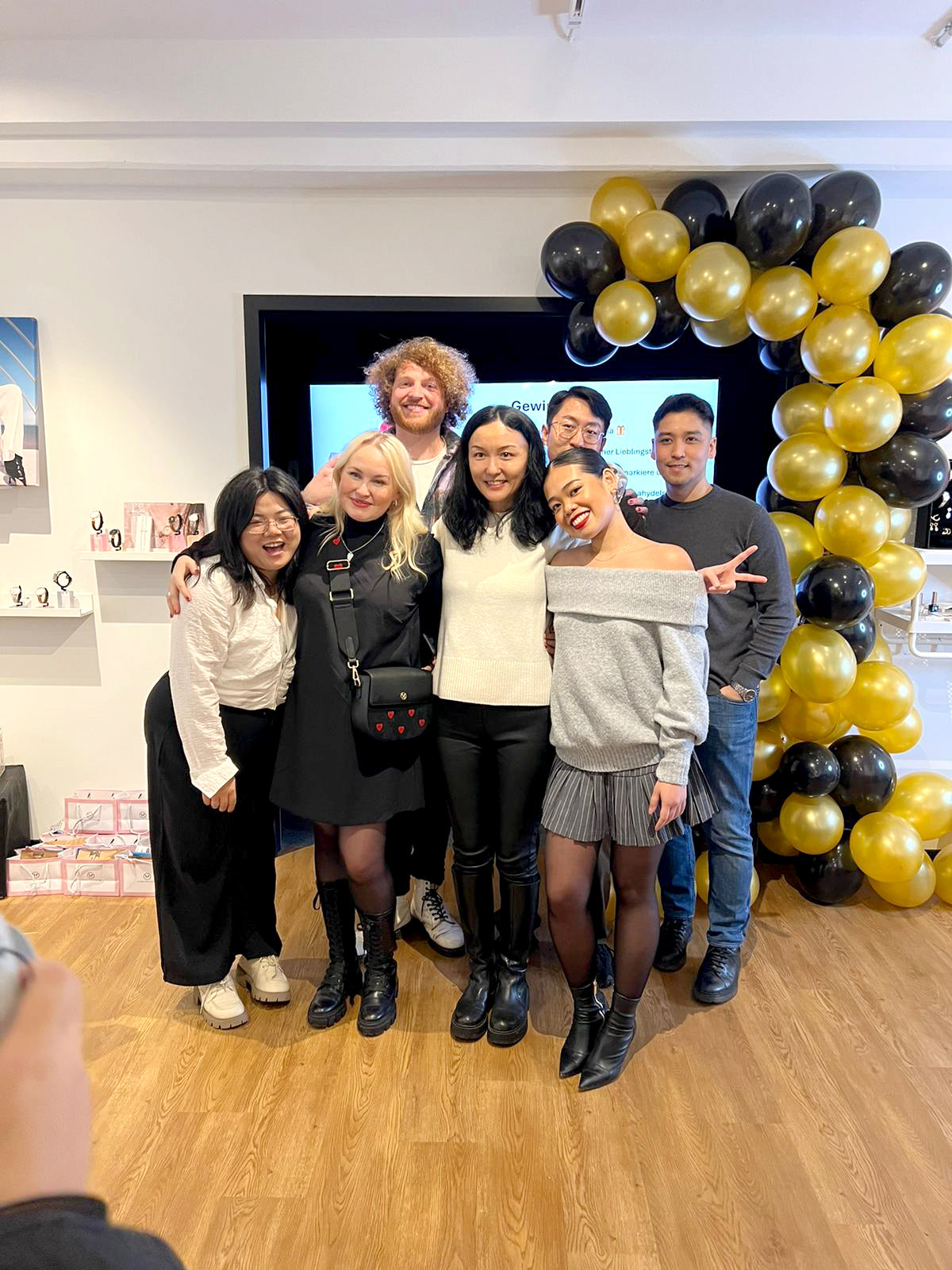 Gruppenfoto des Teams von Victoria Hyde London mit der Gründerin in der Mitte. Das Bild repräsentiert die professionelle und vielfältige Familie hinter den "New Work"-Accessoires von VHL.