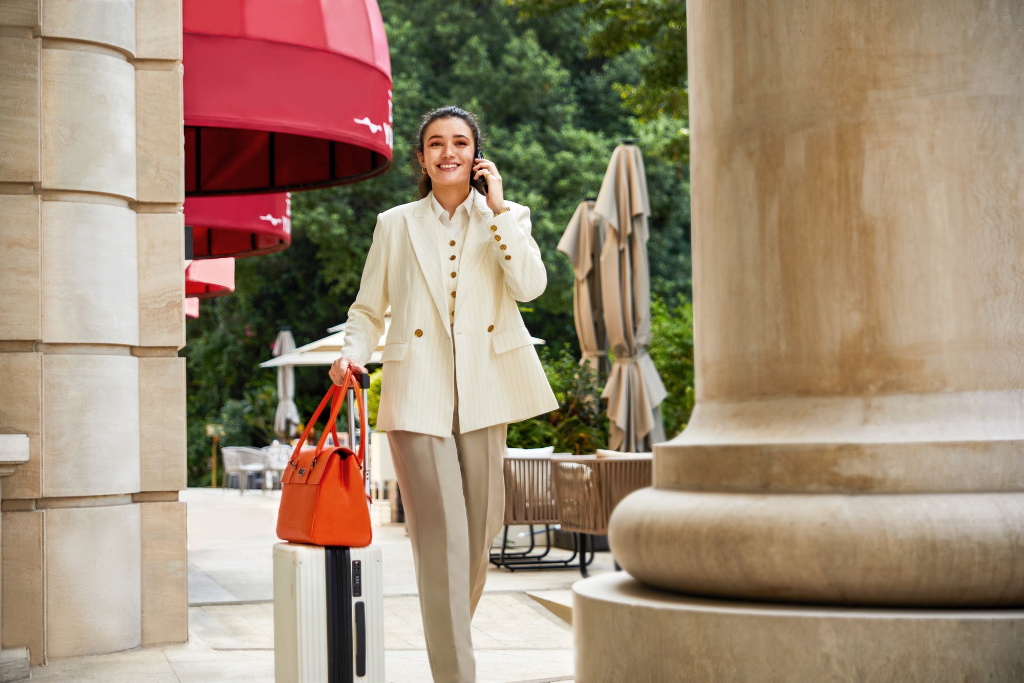 Stilvolle Frau mit Victoria Hyde New Work Bag Jolene, die dank integriertem Gepäckriemen sicher und komfortabel auf dem Reisekoffer befestigt ist.